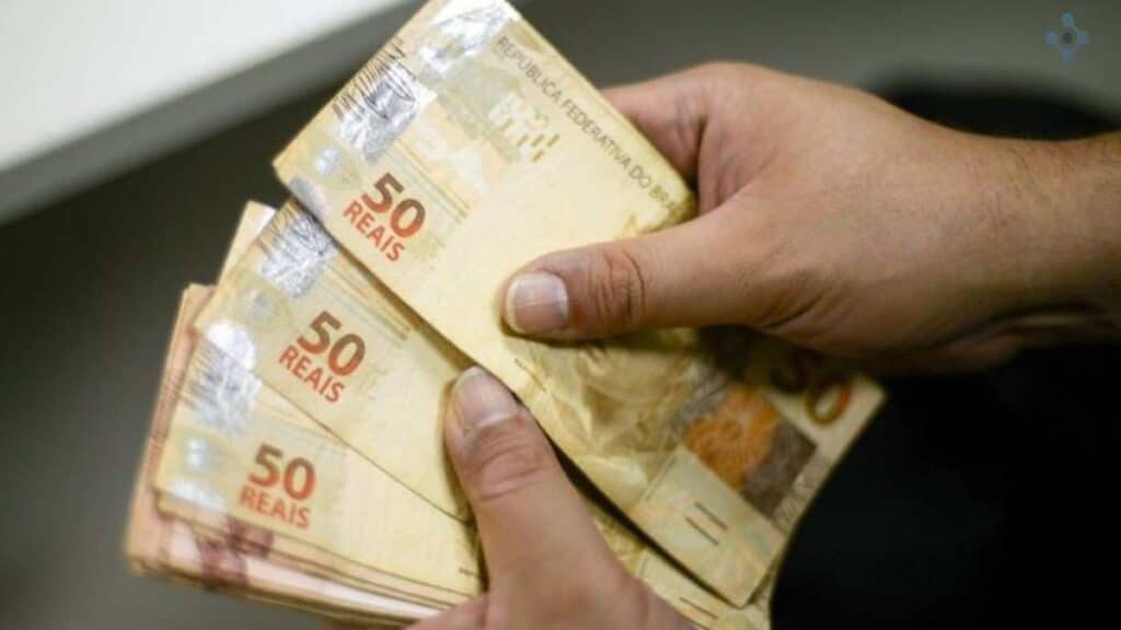 Uma imagem de mãos masculinas segurando notas de dinheiro.