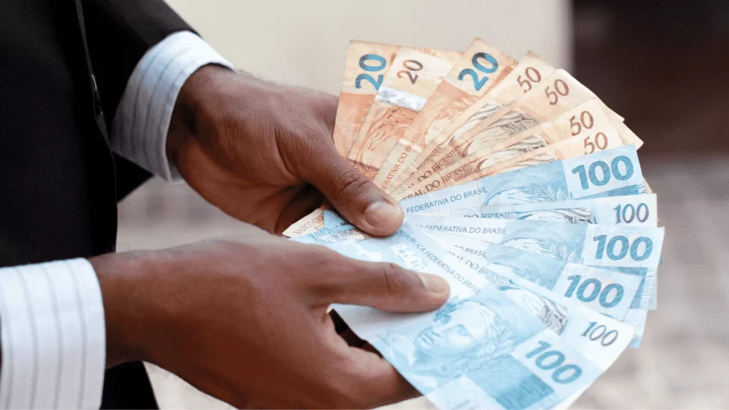 Uma imagem de mãos masculinas segurando notas de dinheiro.