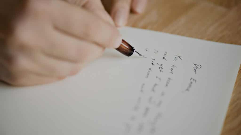 Uma imagem que ilustra uma mão escrevendo uma carta.