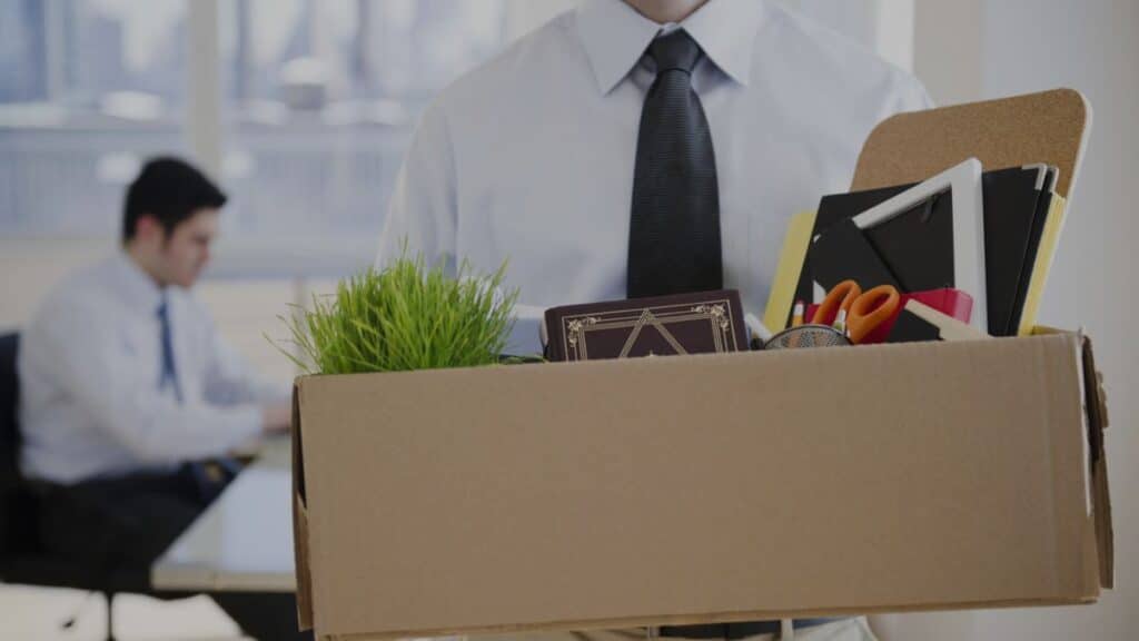 Uma imagem que ilustra uma pessoa segurando uma caixa de papelão com suas coisas dentro.