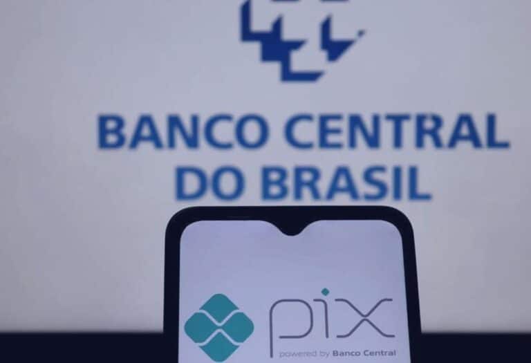Uma imagem que ilustra um celular com o logo do PIX na tela e ao fundo uma parede escrito banco central do Brasil.